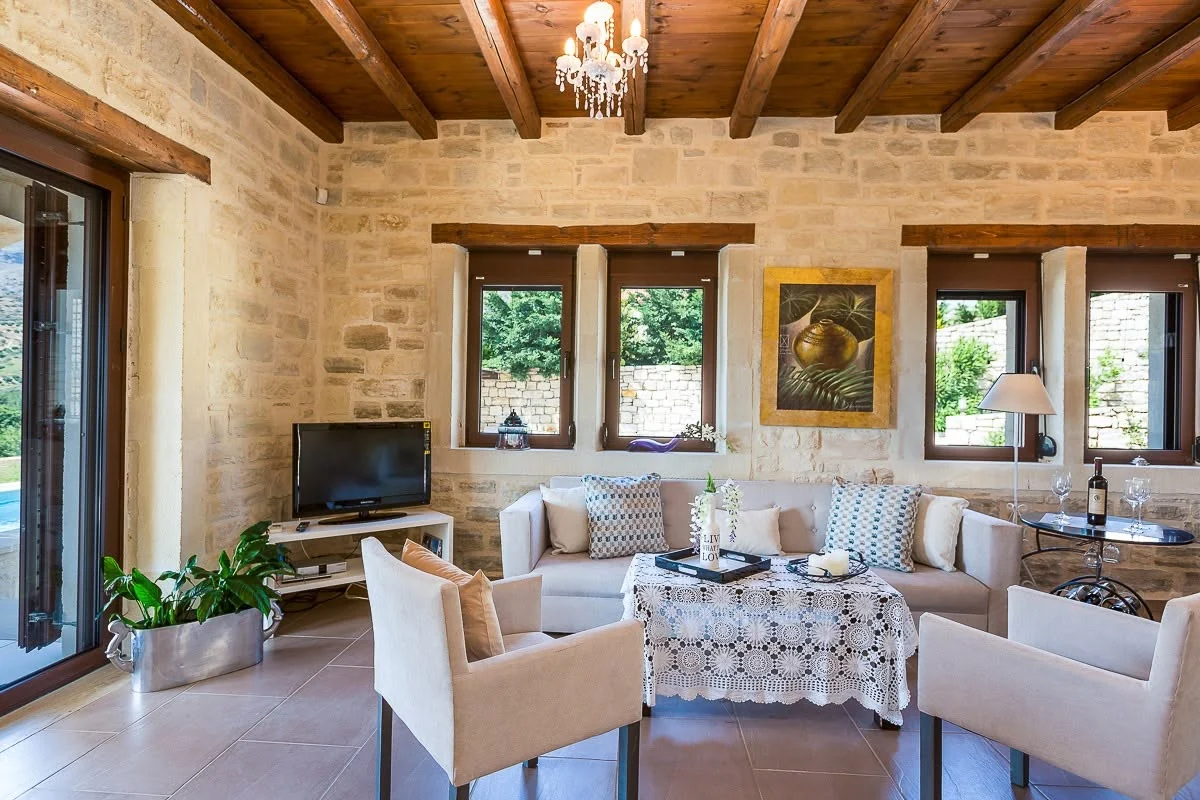 Living and dining area with stone walls and wood-beamed ceiling