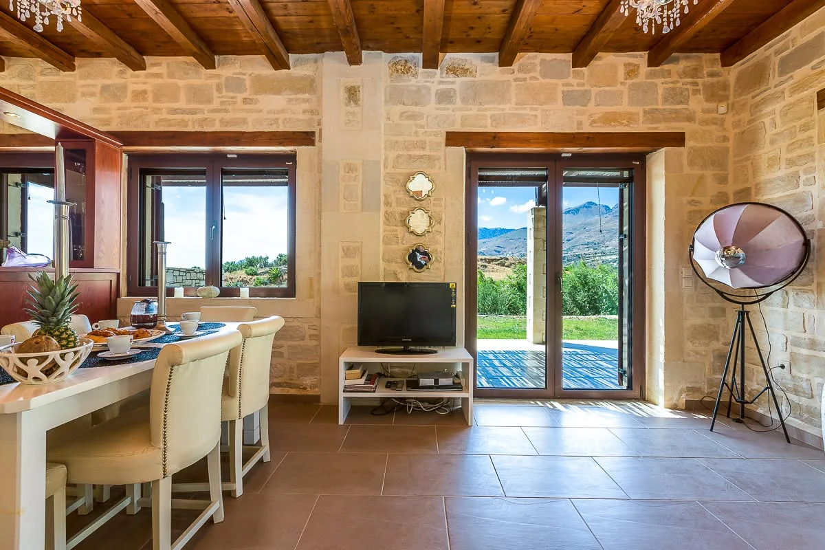 Living and dining area with stone walls and wood-beamed ceiling
