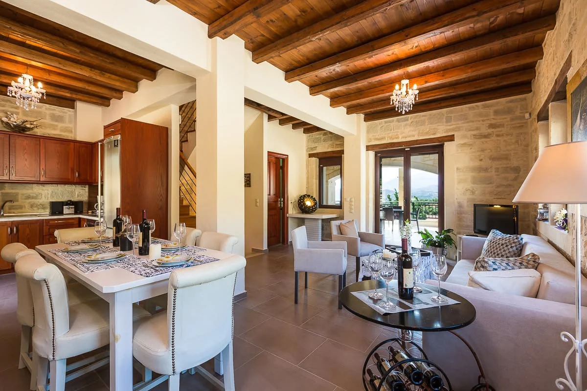 Living and dining area with stone walls and wood-beamed ceiling
