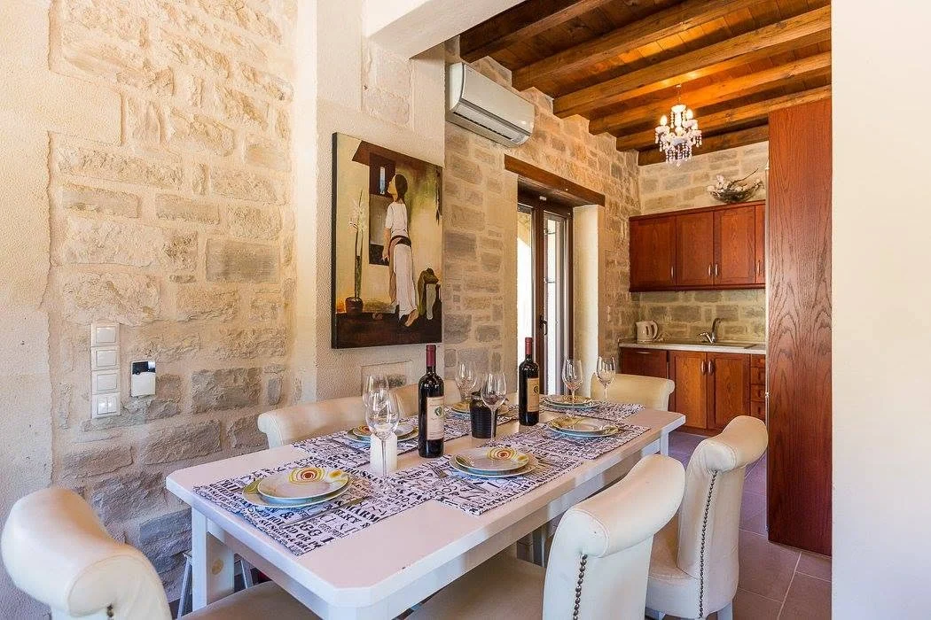 Living and dining area with stone walls and wood-beamed ceiling